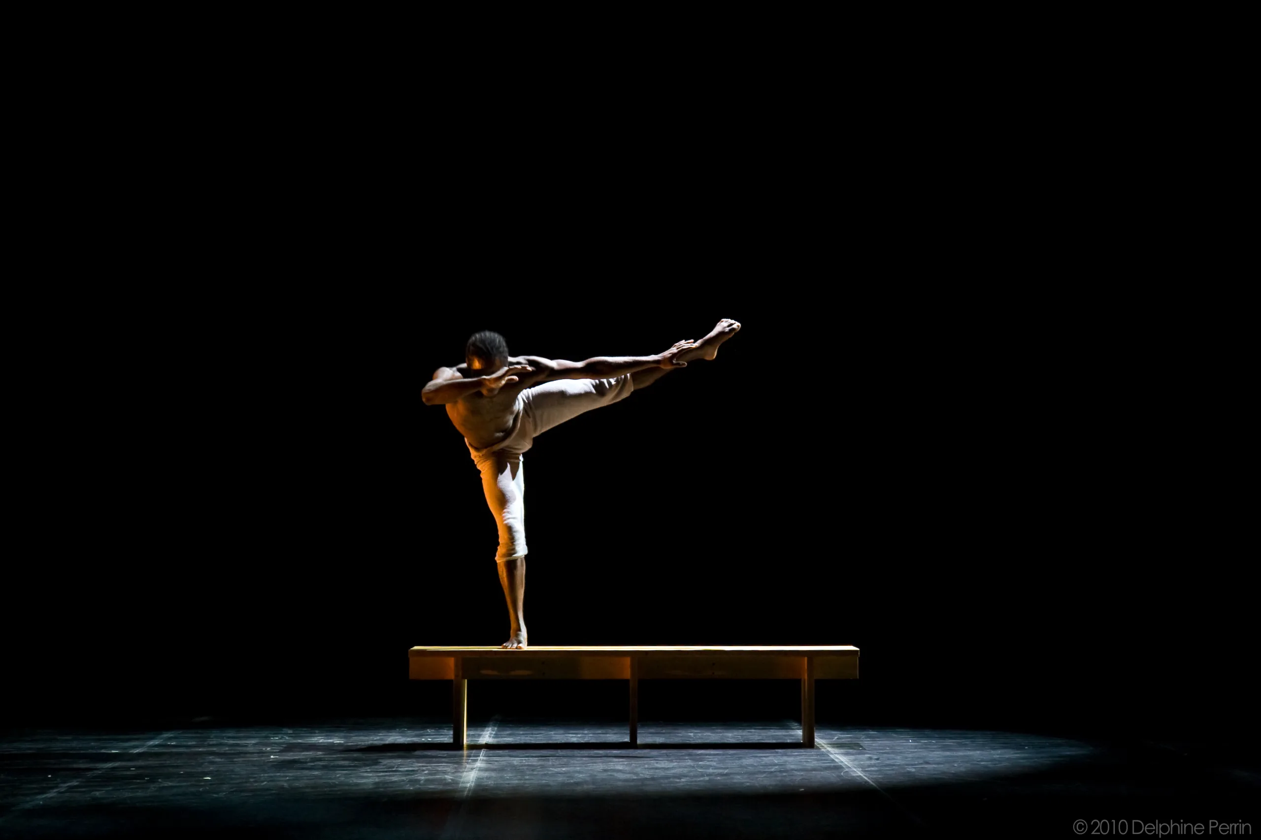 Danseur debout en équilibre sur un banc, un bras tendu